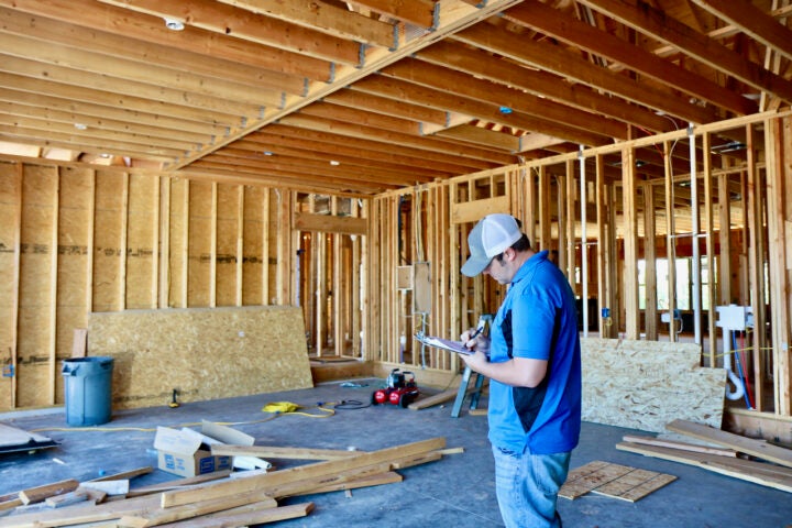 Building inspector writing on a clipboard in an unfinished building